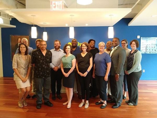 A dozen people standing together and smiling for a camera.
